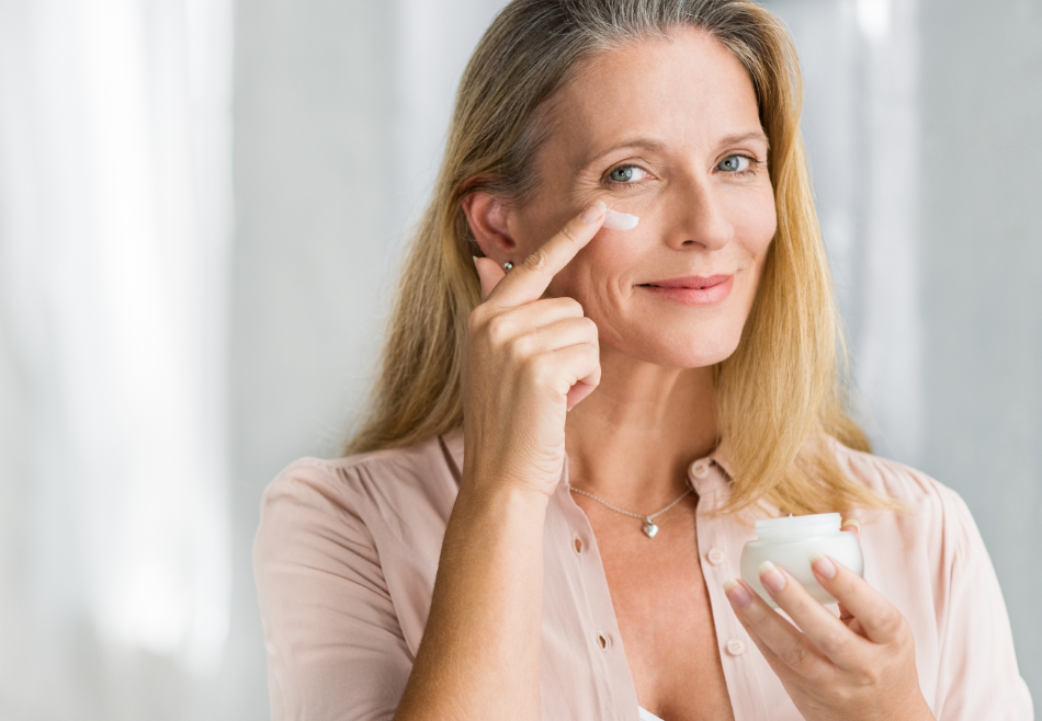 Middle aged woman going through her skin care routine, applying a lotion or cream